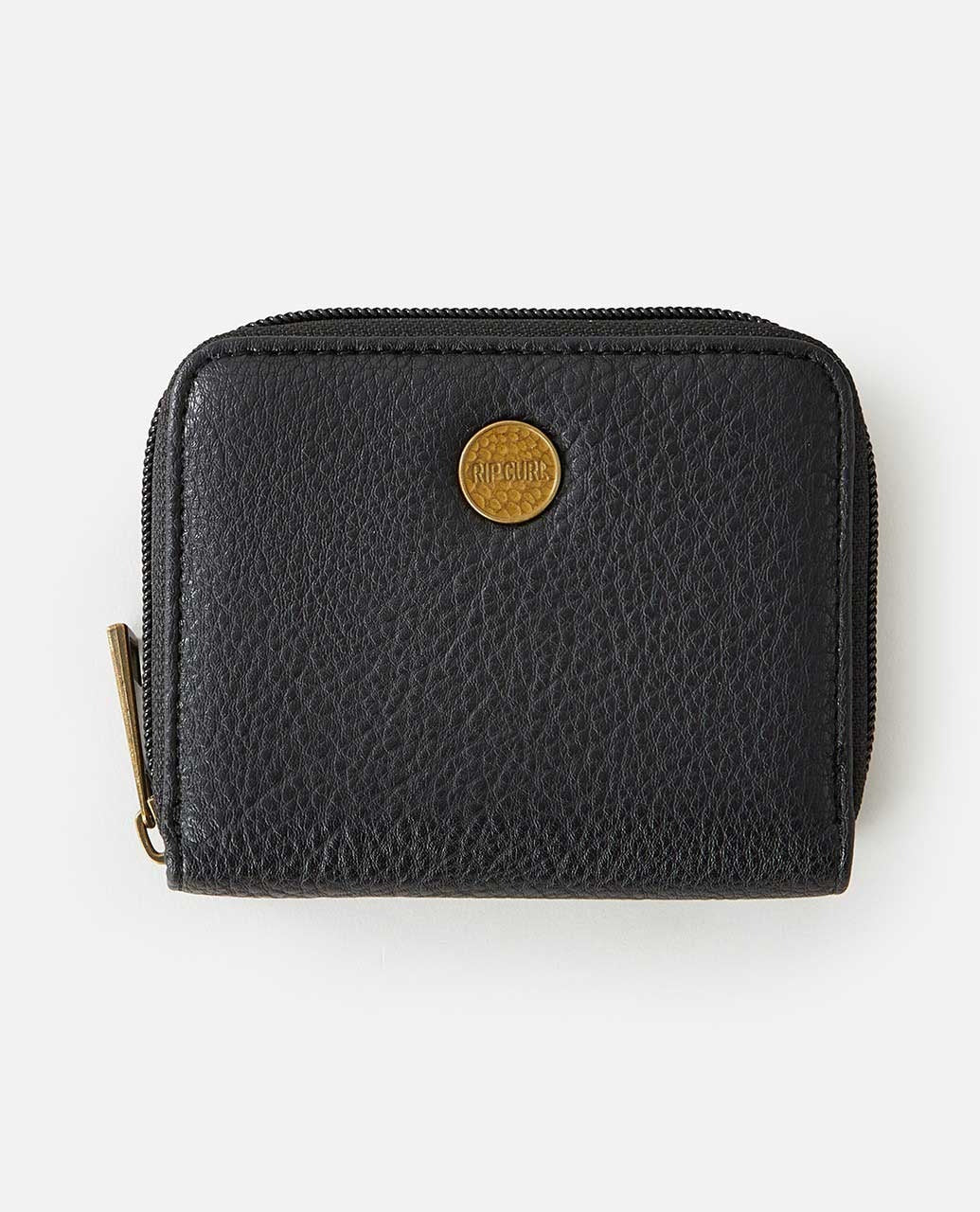 The Rip Curl Wanderer Small Zip Wallet showcases black leather texture and a brass emblem on the front. This minimalist design features a zipper closure with a metal pull tab, set against a plain white background to enhance its sleek sophistication.
