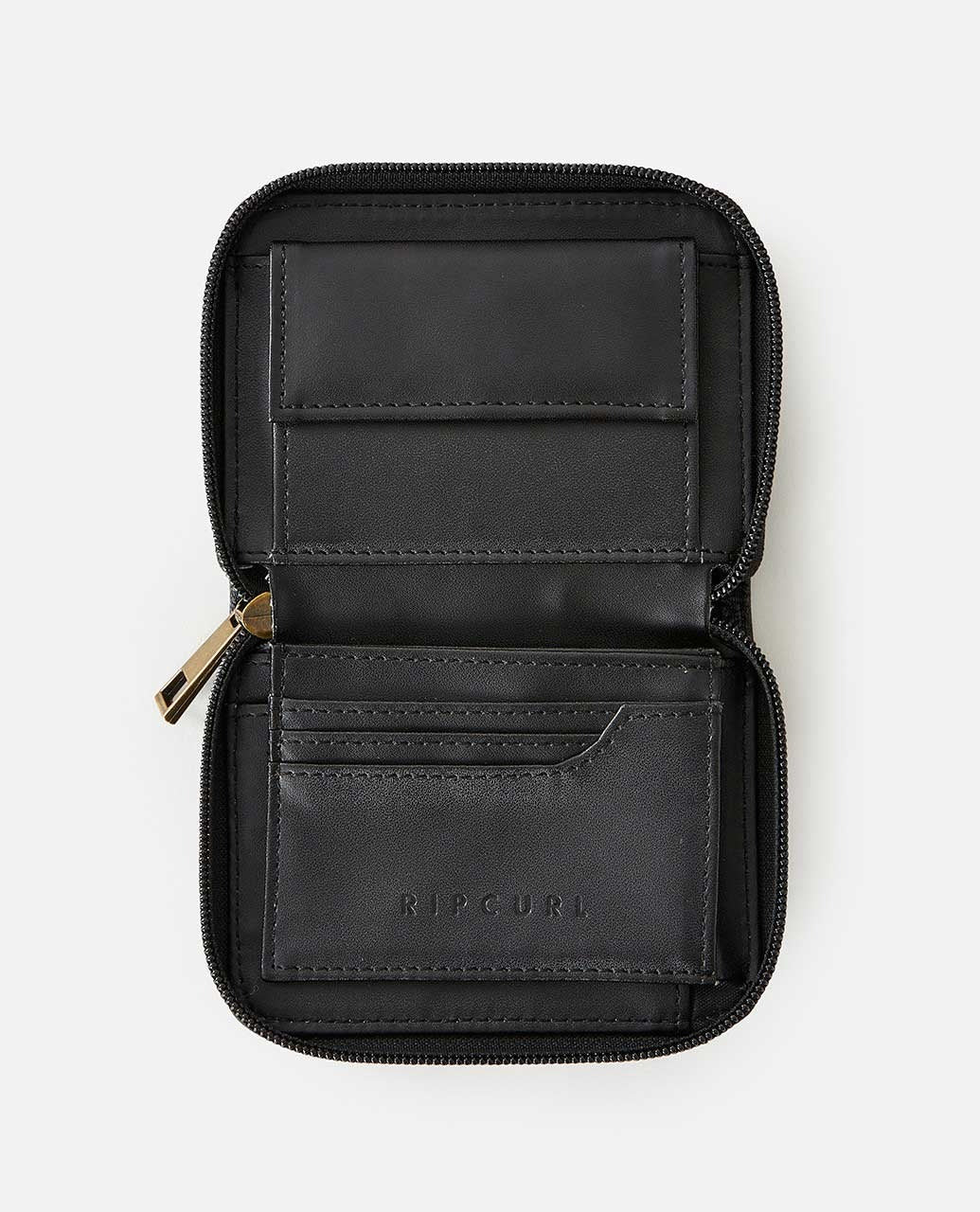 The Rip Curl Wanderer Small Zip Wallet, in black leather with "RIP CURL" embossed on the lower pocket, showcases minimalist design. It offers multiple card slots and a secure zippered edge, combining simplicity and functionality against a plain white background.