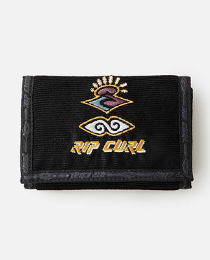 The Rip Curl Archive Cord Surf Wallet is a black wallet that showcases the Rip Curl logo on the front, featuring a stylized wave and sun design above the brand name "Rip Curl" in orange and white letters. It has a fabric texture with visible stitching along the edges and a Velcro closure.
