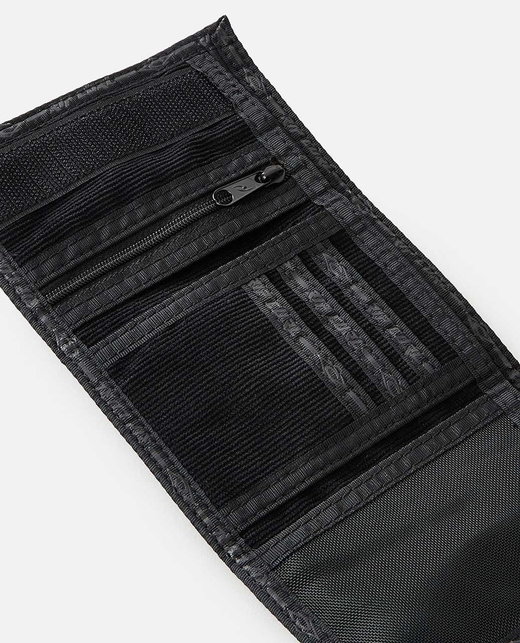 A black tri-fold Rip Curl Archive Cord Surf Wallet is unfastened to showcase its interior features, including a zippered pocket, numerous card slots, a velcro closure, mesh sections, and an ID window. The wallet boasts a textured pattern with visible stitching details along the edges.