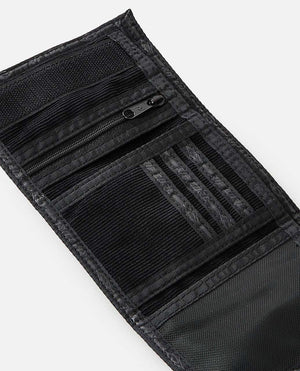 A black tri-fold Rip Curl Archive Cord Surf Wallet is unfastened to showcase its interior features, including a zippered pocket, numerous card slots, a velcro closure, mesh sections, and an ID window. The wallet boasts a textured pattern with visible stitching details along the edges.