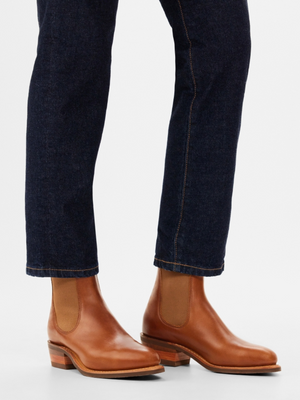 A person wearing dark blue jeans and RM Williams Lady Yearling Rubber Sole Boots with a height-enhancing heel, standing against a plain white background.