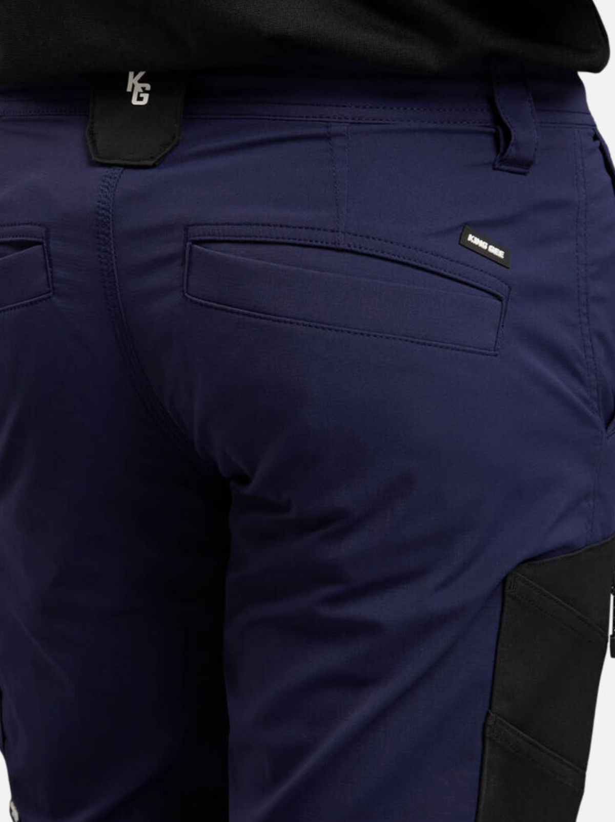 The King Gee Trademark Cargo Pant in navy blue, made from durable ripstop fabric with black accents, features a moisture control system, back pockets with flaps, and a visible tag near the right pocket—ideal for work or outdoor activities.