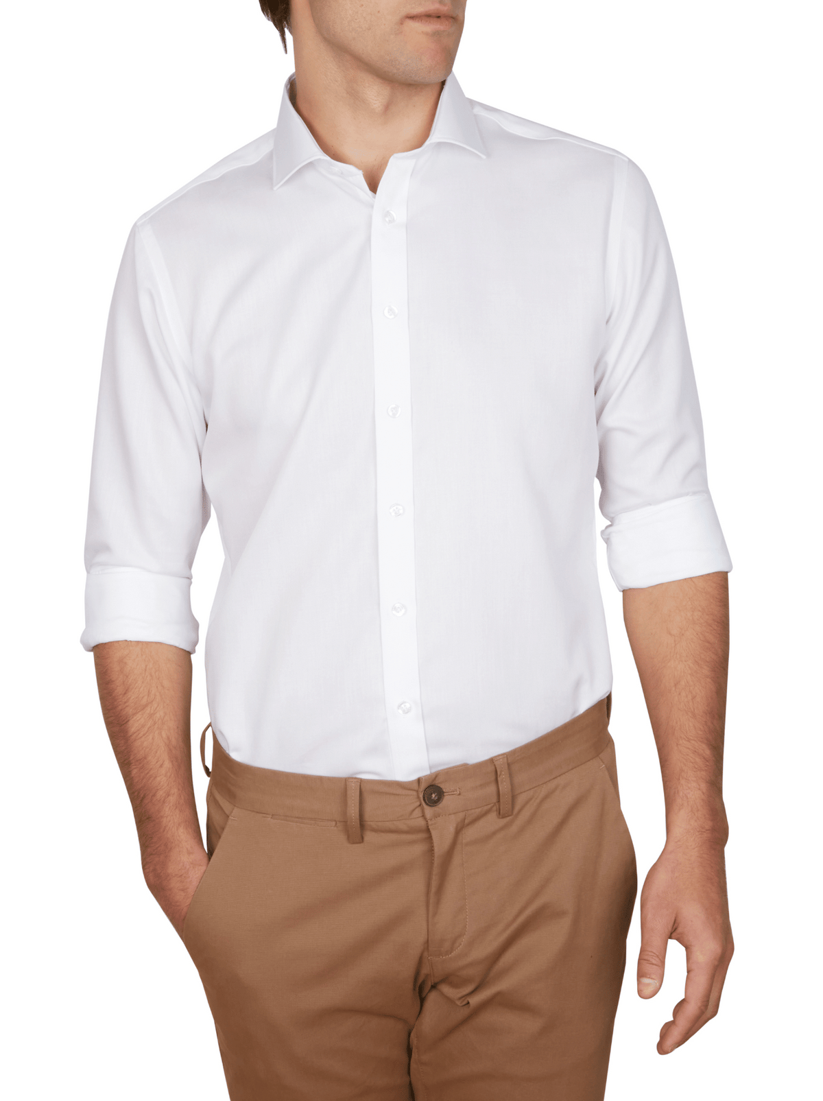 A man wears an Abelard Non Iron Cotton Twill Slim Fit Shirt with a cutaway collar. The crisp white shirt, untucked over tan pants, is styled with rolled-up sleeves as he rests his left hand in his pocket against a plain white backdrop.