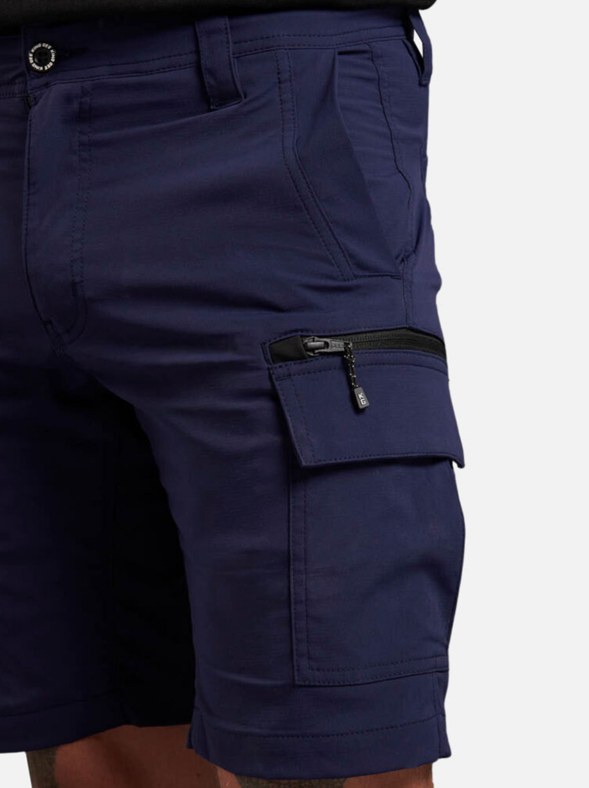 Someone wearing navy King Gee Trademark Cargo Shorts, crafted from stretch ripstop fabric with a zippered pocket, stands against a white background. These shorts offer comfort and durability with their button and zipper fly design.