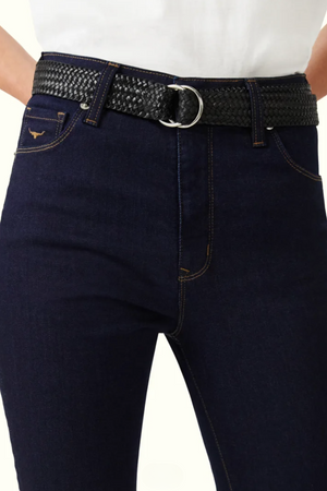 A person wearing the RM Williams Albury Jean in dark blue, a high-rise skinny fit made from stretch cotton with contrast stitching and a small decorative Longhorn embroidery on the front pocket. The jeans are paired with a black braided belt featuring a silver buckle, and they have tucked in a white top.