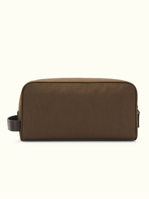 The RM Williams Hawkesbury Washbag is a rectangular, brown waxed cotton travel bag with a simple design, dark brown side handle, and zippered closure, displayed against a light beige background.
