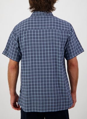 A person with medium-length brown hair is seen from behind, wearing the Swanndri Russell Shirt in blue and white checks, made of 100% cotton with a relaxed fit. The background is plain white.