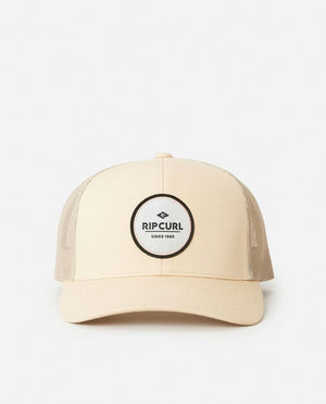 Beige Rip Curl Routine Curve Trucker hat featuring mesh sides and a circular "Rip Curl Since 1969" logo patch on the front, shown against a plain white background.