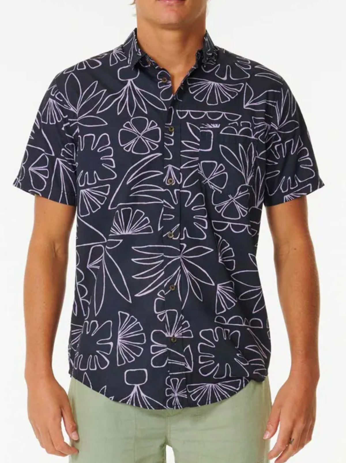 A person wearing a Rip Curl SWC Short Sleeve Shirt featuring a white abstract floral pattern and light green pants stands against a plain white background.
