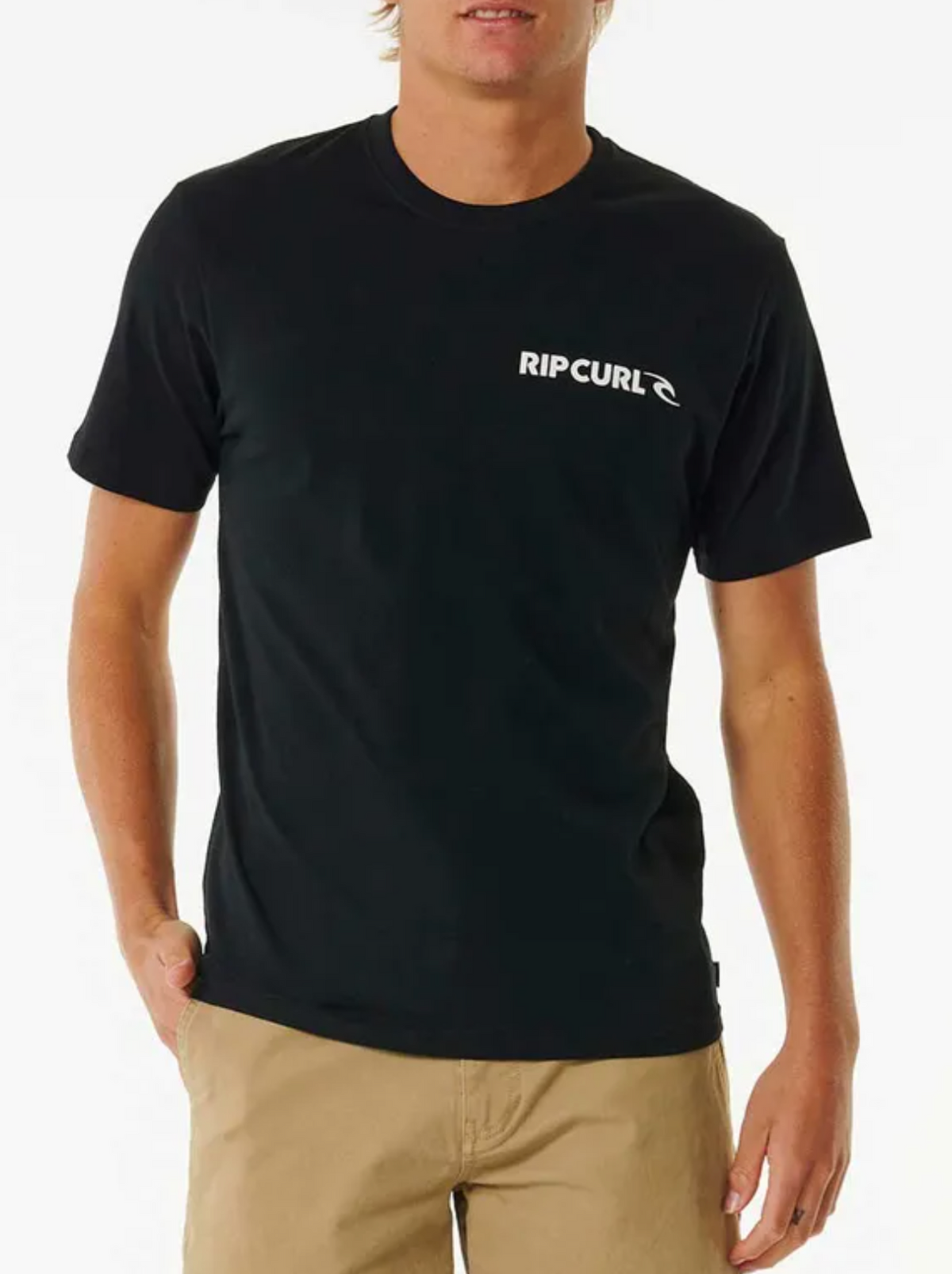 A person wearing the black Rip Curl Brand Icon Tee, 100% cotton with a white logo on the chest, is paired with beige shorts against a plain white background, highlighting their casual style.