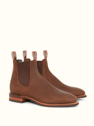 The RM Williams Comfort Craftsman Boot is a brown leather Chelsea boot with elastic side panels, back pull tabs, and a low wooden heel, made in Australia and shown on a plain light background.