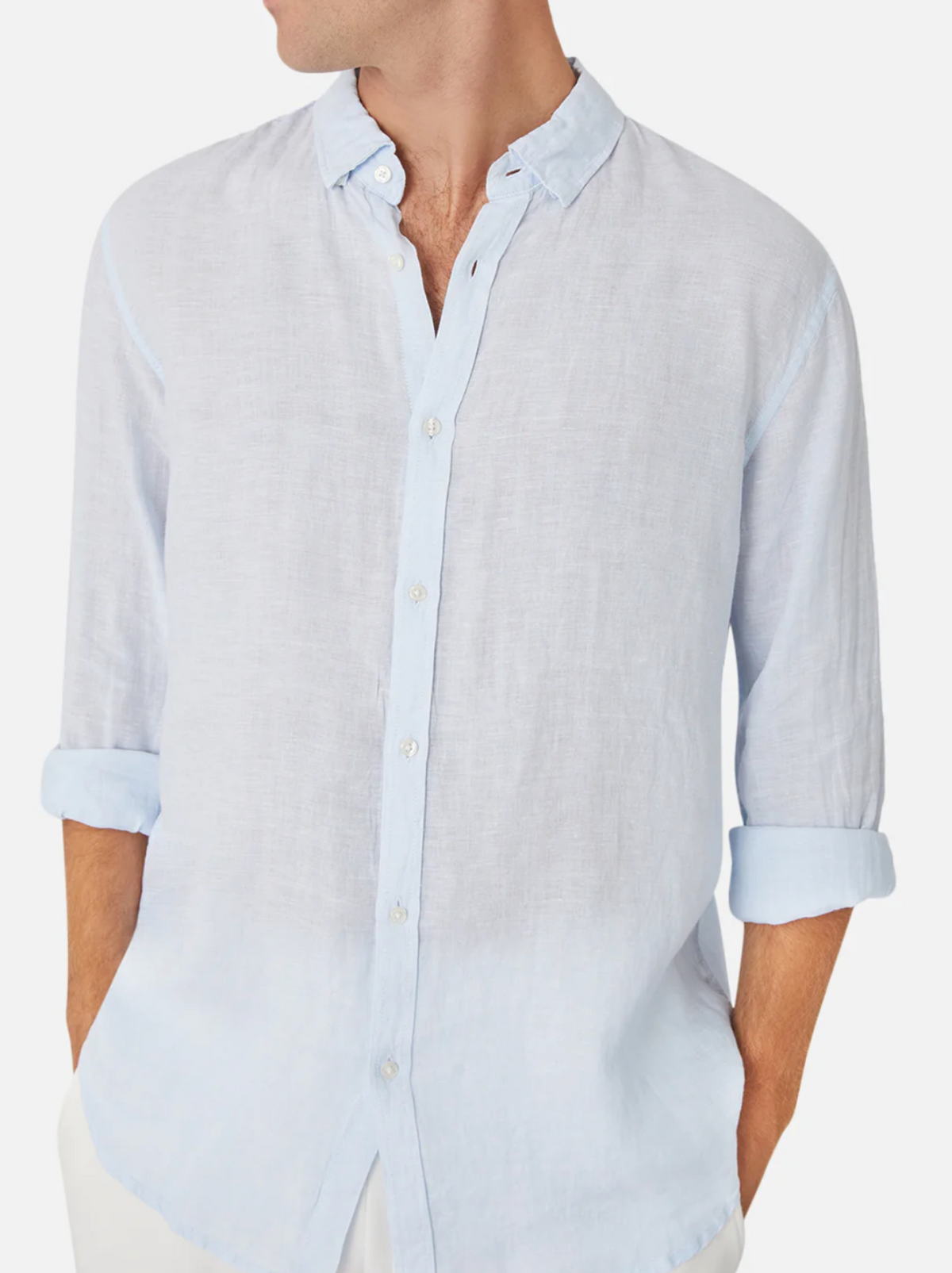 A person wears the Industrie The Tennyson Linen Shirt in light blue, sleeves rolled up. The image focuses on the upper body with their head turned to the side, showcasing the shirt's relaxed fit and casual style.