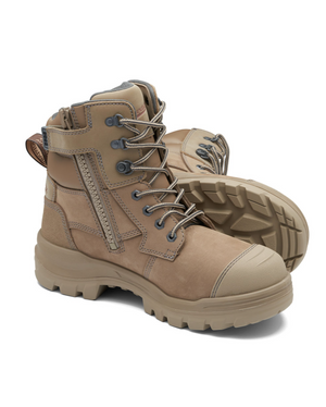 The Blundstone RotoFlex 8063 Zip Sided Safety Boot with thick rubber soles, metal eyelets, and laces is displayed. One boot stands upright while the other lies on its side, showcasing the tread pattern. Made from water-resistant nubuck leather, these safety boots feature side zippers and reinforced toe caps.