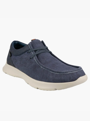 The Florsheim Bushwacker Canvas Slip On is a men's casual shoe featuring a blue organic cotton upper, white rubber sole, and contrast stitching, displayed from the front against a plain white background.