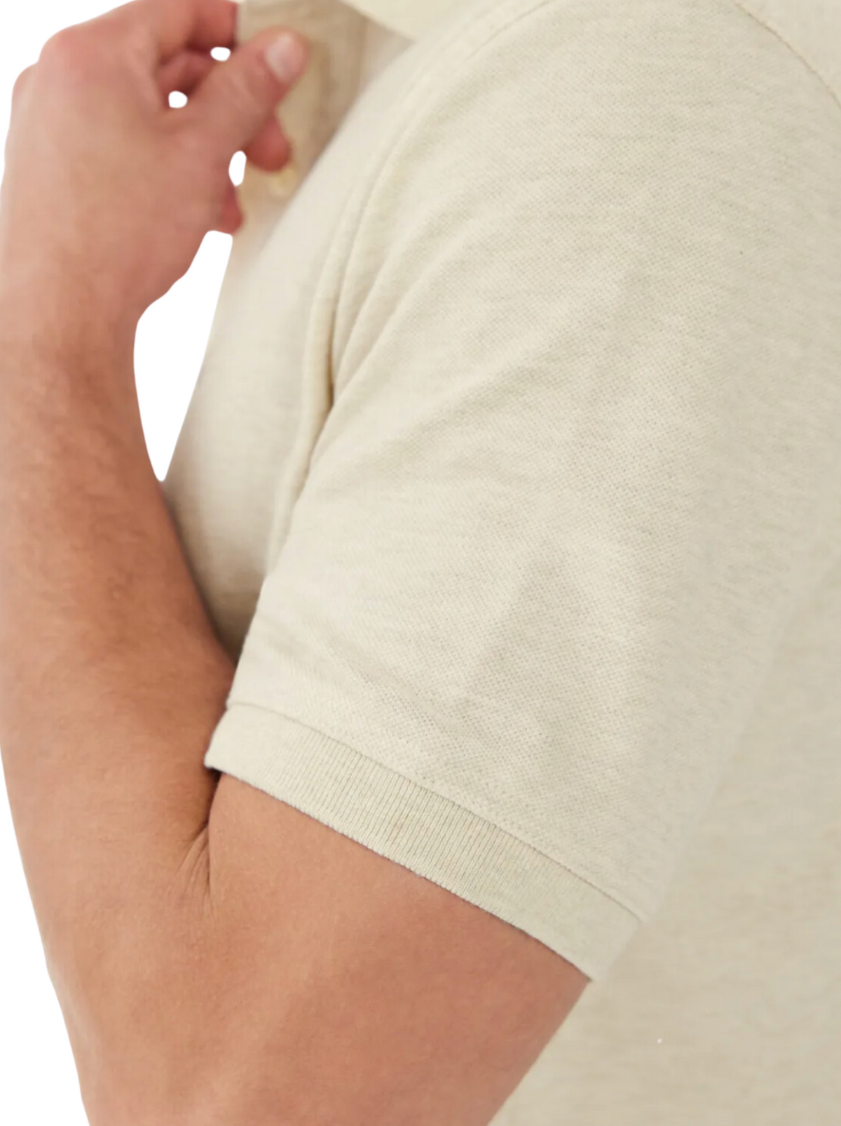 Close-up of a person wearing the RM Williams Rod Polo in light beige, touching the collar. The focus is on the arm and sleeve, highlighting the breathable cotton pique texture and comfortable fit.