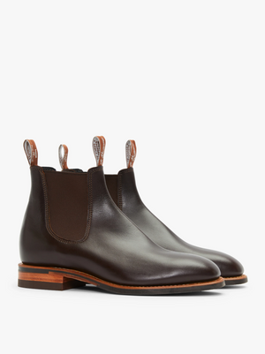 A pair of RM Williams Dynamic Flex Craftsman Boots in dark brown Yearling leather, featuring elastic side panels, pull tabs with a logo or pattern, and stacked wooden heels. The boots boast a sleek, polished finish and stitching details along the sides.