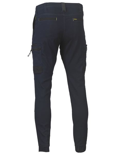 Back view of Bisley Flex & Move Stretch Denim Cargo Cuffed Pant in dark blue denim, featuring multiple cargo pockets—zippered and flap—on legs and back, with fitted cuffed ankles.