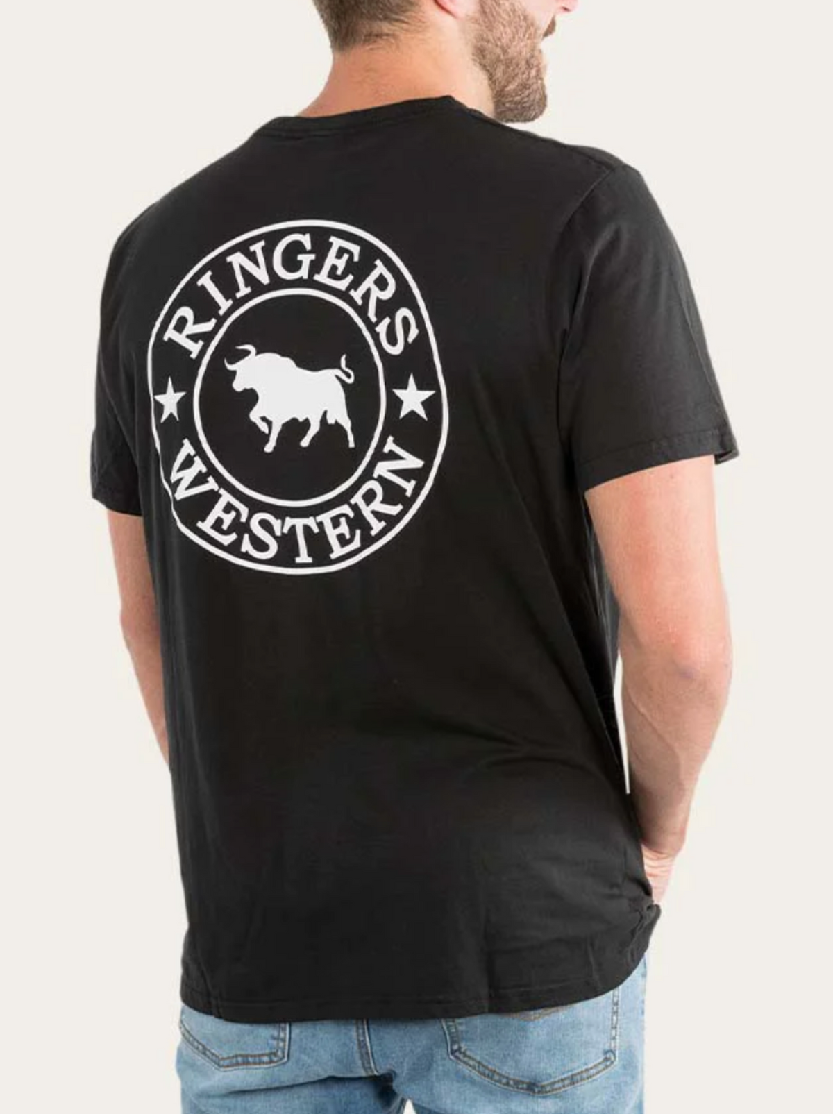 A man wears a black Ringers Western Signature Bull Loose Fit T-Shirt, 100% cotton jersey with a large white bull logo on the back, paired with light blue jeans.