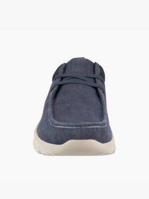 Front view of the Florsheim Bushwacker Canvas Slip On, a casual blue shoe with dark laces and a light beige sole, made from organic cotton, displayed against a plain white background.