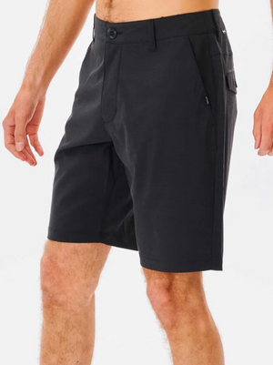 A person wears black Rip Curl Boardwalk Phase Nineteen Shorts with front pockets and a button closure, shown from mid-torso to knees against a white background.