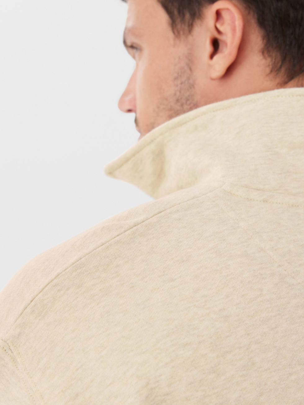 Close-up of a man wearing the RM Williams Mulyungarie Fleece jacket in light beige, collar turned up. His face and neck are visible from the side, with a plain, light background.