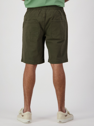 A person faces away from the camera in Swanndri Clevedon Stretch Canvas Shorts, showcasing two back pockets. Paired with white sneakers and a matching green shirt, this outfit stands out against a plain white backdrop, emphasizing the relaxed comfort of elastic waist shorts.