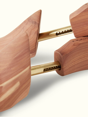 Close-up of RM Williams Red Cedar Boot Tree featuring golden metal rods. The smooth, natural finish highlights the grain pattern. Its ergonomic design maintains shoe shape and absorbs moisture, making it perfect for leather care.