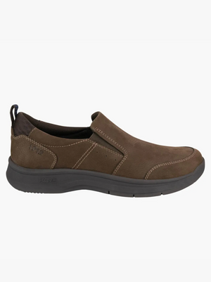 The Florsheim Mac Mocc Slip On is a brown slip-on casual shoe with contrast stitching, KORE Technology for comfort, a black heel pull tab, and a thick dark gray cushioned sole that blends classic style with modern design.