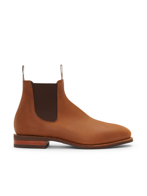 The RM Williams Comfort Craftsman Boot is pictured from the side against a white background. This handmade, single Chelsea boot in brown nubuck leather features a low heel, elastic side panels, and pull tabs for added style and texture.