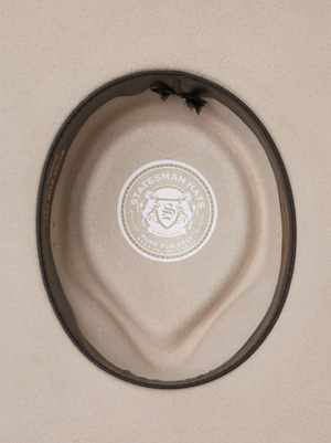 A top-down view of the Statesman Big Australian Fur Felt Hat in beige, featuring a brown leather band. Inside, the lining displays a circular "Statesman Hats" logo with two lions and the words "Pure Fur Felt.