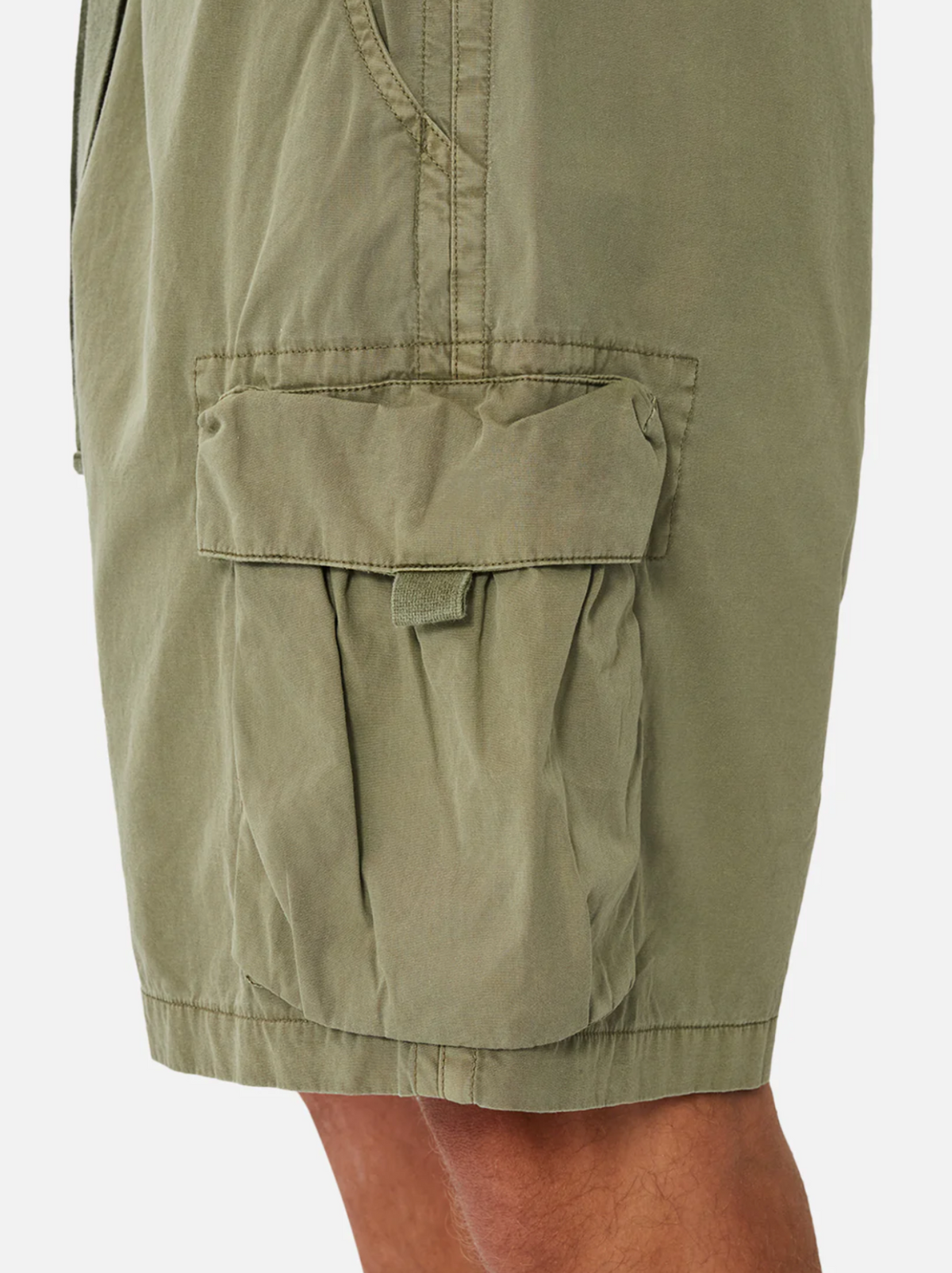 Close-up of the Industrie The Del Sur Combat Short in olive green, featuring a flap pocket with Velcro closure. Visible stitching and creases create a rugged look. Made from 100% cotton with multiple pockets, it’s styled to show a glimpse of the wearer's leg.