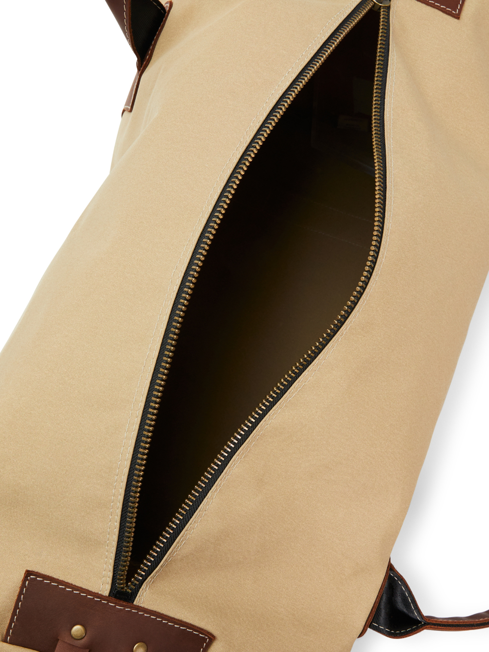 The RM Williams Sorrento Ute Bag features a beige, water-repellent utility canvas with a partially open brown zipper that reveals a spacious interior. The edges are trimmed with brown leather and metal studs, and dark brown handles from R.M. Williams are attached to the sides.
