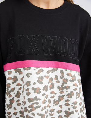 Wearing the Foxwood Split Crewβa crew neck sweater with bold "FOXWOOD" text, a pink stripe, and a white panel featuring brown and black leopard printβadds a stylish touch to any casual outfit.