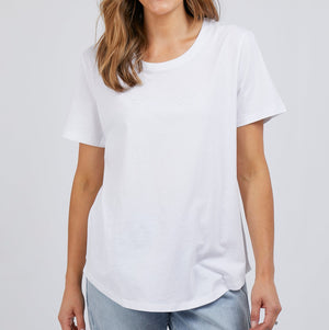 Wearing a Foxwood Tee, renowned for its relaxed fit and 100% cotton fabric, paired with light blue jeans, an individual with long hair stands gracefully against a plain white background.