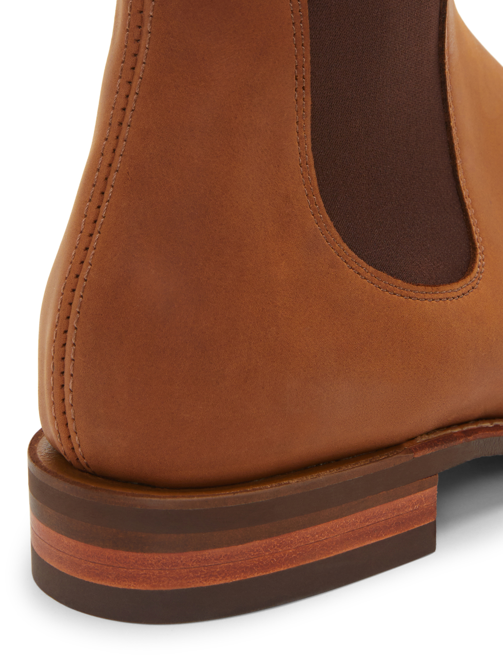 Close-up of the RM Williams Comfort Craftsman Boot in tan, crafted with nubuck leather. It showcases the heel and elastic side panel with detailed stitching and a layered wooden heel, highlighting its craftsmanship and stylish design.