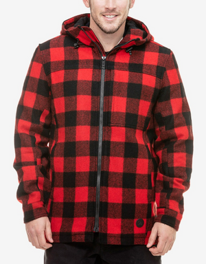 A person wearing a Swanndri Hudson Hoody, featuring a red and black checkered pattern and a front YKK zip, stands and smiles against a plain white background. The jacket, made from 100% New Zealand Wool with a plaid design, has their hands comfortably placed in the pockets.
