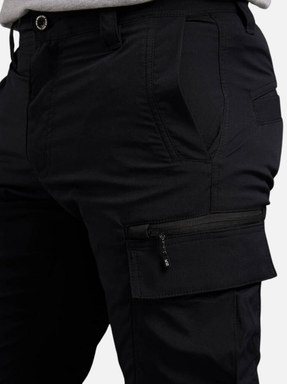 Close-up of a person wearing black King Gee Trademark Cargo Pant featuring a zipper thigh pocket, hands in side pockets, belt loops, detailed stitching, and enhanced durability.