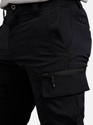 Close-up of a person wearing black King Gee Trademark Cargo Pant featuring a zipper thigh pocket, hands in side pockets, belt loops, detailed stitching, and enhanced durability.
