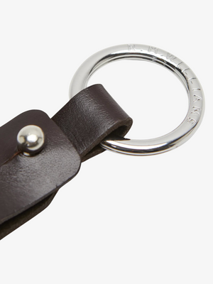 A close-up of the RM Williams Pioneer Key Fob featuring a dark brown double butt leather strap and a silver metal ring engraved with "R.M.WILLIAMS" around the edge.