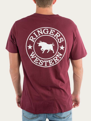 A person is wearing a maroon Ringers Western Signature Bull Loose Fit T-Shirt, made from 100% Cotton Jersey, with "Ringers Western" and a circular logo featuring a bull in the center printed in white on the back. They are also wearing blue jeans, set against a plain white background.