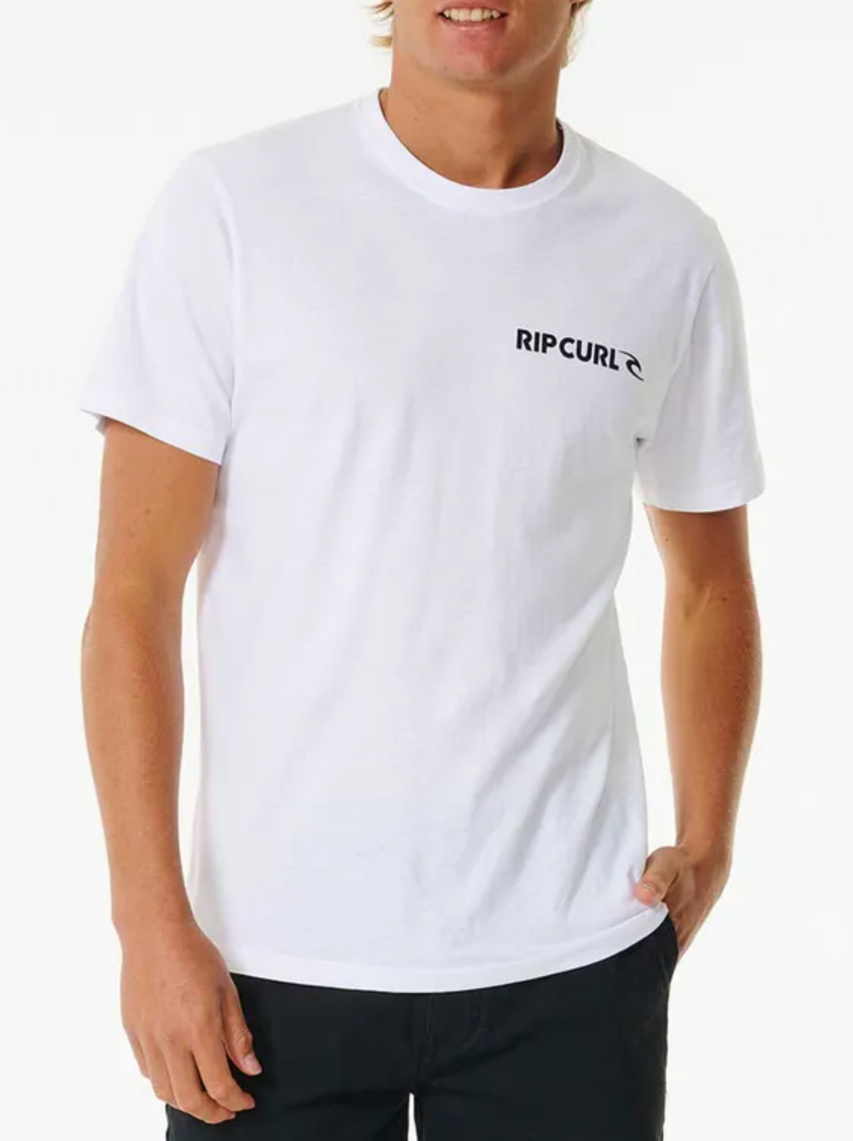 A person in a white Rip Curl Brand Icon Tee, made of 100% cotton for comfort, poses against a plain background. The T-shirt displays black text on the upper left side. They're wearing dark pants with one hand casually in their pocket.
