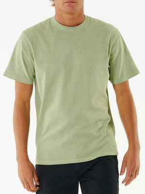 Wearing a light green Rip Curl Plain Wash Tee featuring a relaxed fit and crew neckline, paired with black pants, a person stands against a white background with their face partially out of frame.