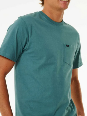 Someone wears the Rip Curl Plain Pocket Tee in teal, made from 100% cotton, standing against a white background—a timeless wardrobe essential.
