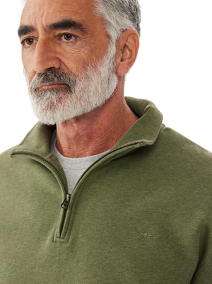 An older man with a gray beard looks to the side, wearing an RM Williams Mulyungarie Fleece—a green quarter-zip sweatshirt with a vintage leather patch—over a gray shirt. The background is plain white.