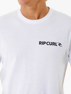Someone is wearing a Rip Curl Brand Icon Tee, made from 100% cotton for comfort. The white tee features the "RIP CURL" logo on the upper left side, with an image showing their upper torso and part of their face.