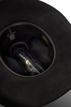 Close-up view inside a black Akubra Rough Rider hat, featuring the inner lining, size label "57," and a transparent plastic insert with gold text and logo.