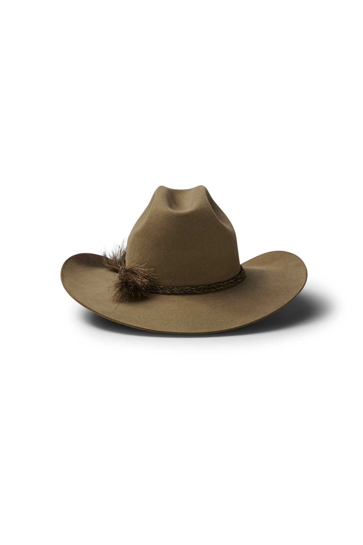 The Akubra Rough Rider is a brown wide-brimmed cowboy hat with a braided band and decorative feather, shown against a white background.