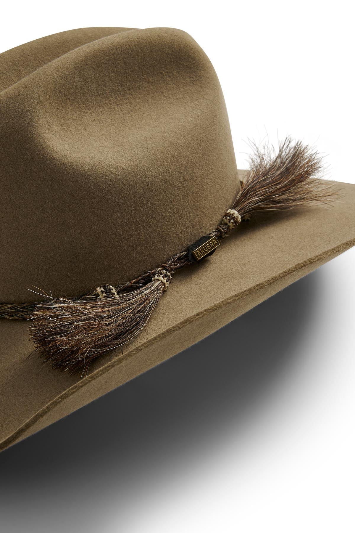 Close-up of the Akubra Rough Rider, a durable brown felt cowboy hat with a braided rope and tassel band, inspired by classic Akubra style; set against a white background.