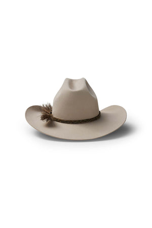The Akubra Rough Rider is a beige, wide-brimmed cowboy hat featuring a braided band and brown feather tuft, displayed on a white background with a subtle shadow—an iconic, durable choice for adventure.